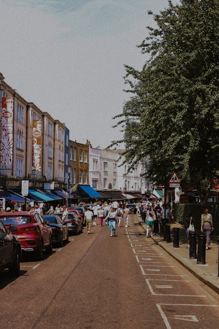 A quiet residential street in Finsbury Park with a row of Victorian-style terraced houses featuring bay windows, decorative brickwork, and chimneys, under a cloudy sky. The pavement runs alongside the